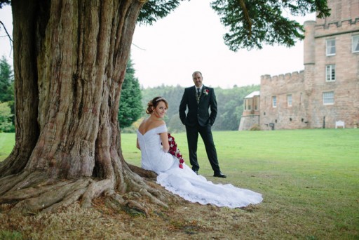 Photo of bride and groom beneath ancient tree in the grounds of a Scottish castle