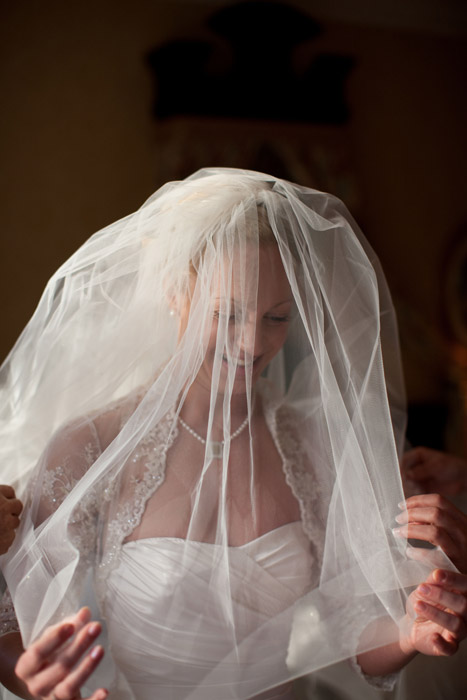Photo of a bride smiling beneath her veil