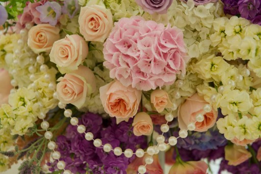 Photo of wedding flowers in shades of pink, purple and cream with strings of pearls