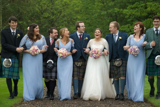 Photo of bride and groom walking up gravel drive arm in arm with bridesmaids, best man and ushers.