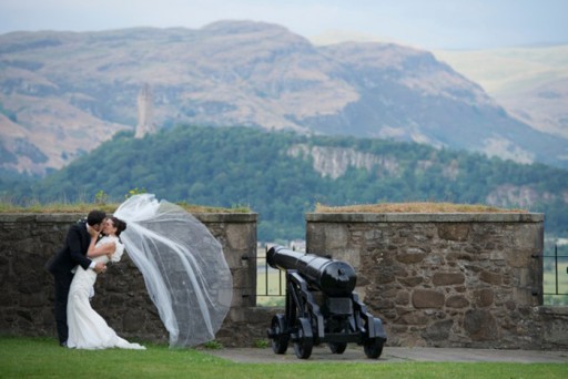 Bride and groom embracing in front of the parapet of a Scottish castle