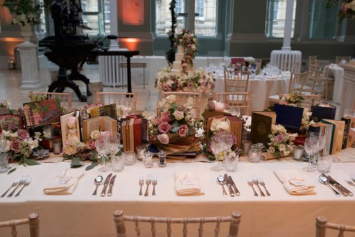 Photo of the head table at a wedding reception decorated with flowers and books
