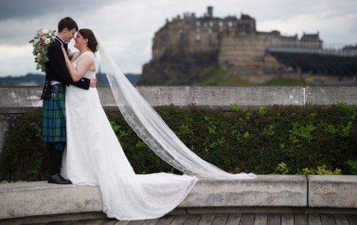 Bride and groom embracing on rooftop with Edinburgh Castle in the background