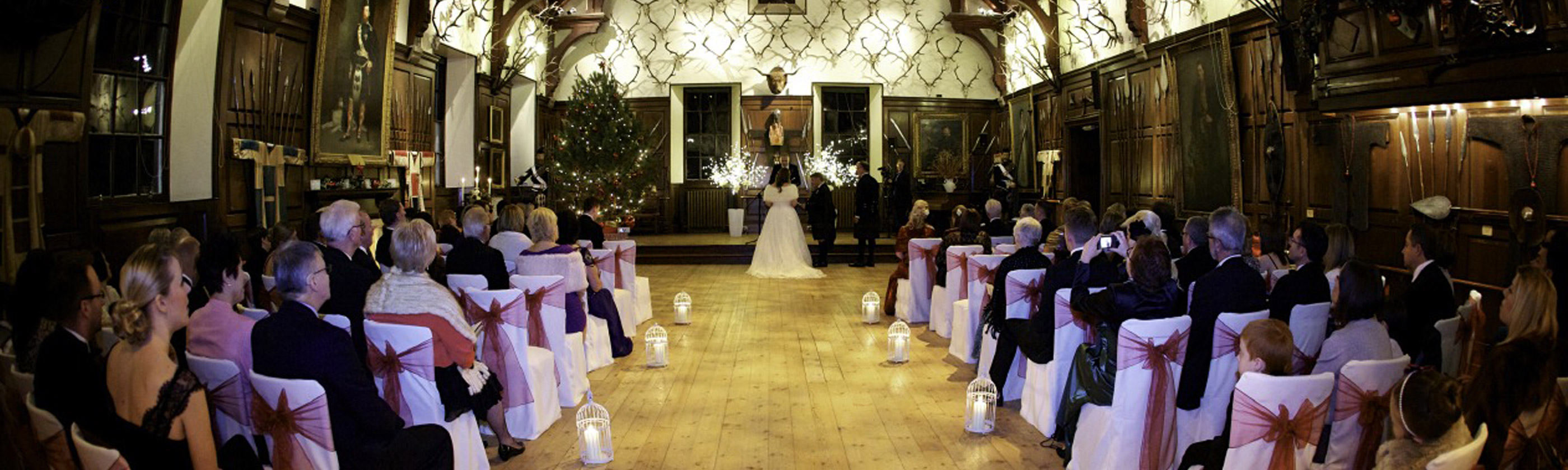 Photo of a wedding ceremony taking place in one of the grand wood paneled halls in Blair Castle