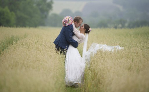 Photo of bride and groom in a hay field embracing