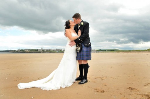 Photo of bride and groom kissing on the West Sands in St Andrews