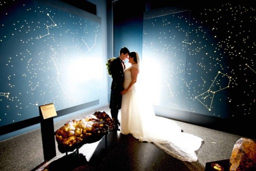 Photo of bride and groom in front of a projection of the sky at night
